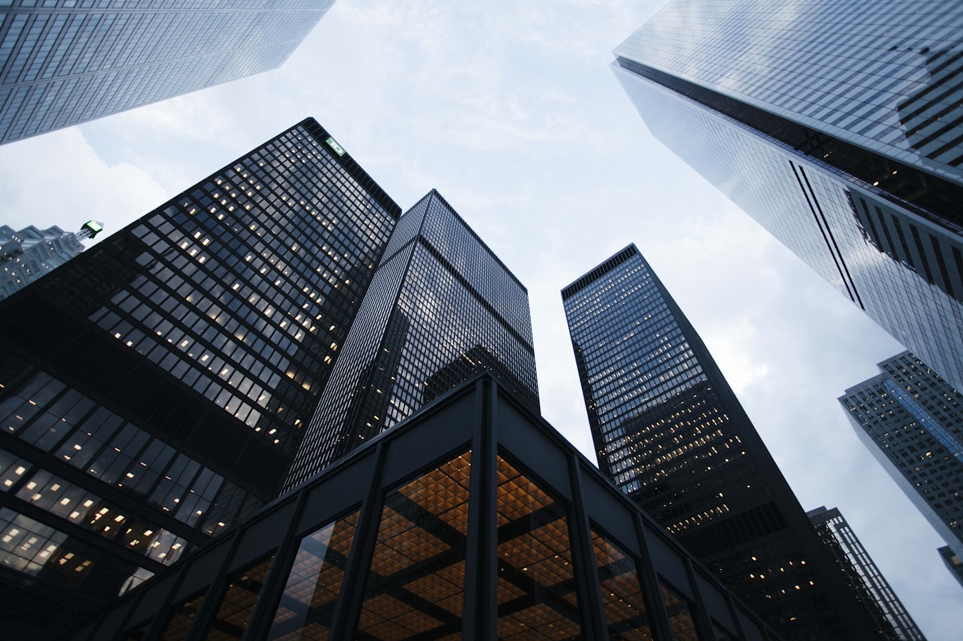 Looking upward between modern glass buildings toward an open sky
